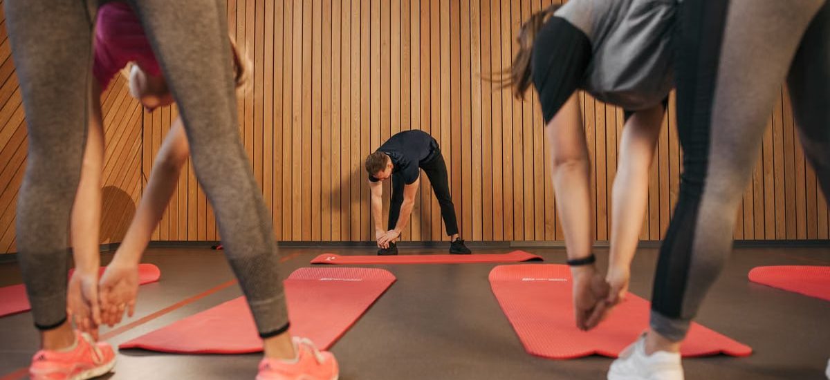 Adults in a gym stretching on yoga mats, promoting fitness and wellness indoors.